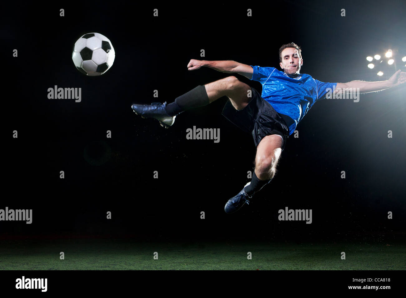 Young soccer player leaping into air to kick ball Stock Photo