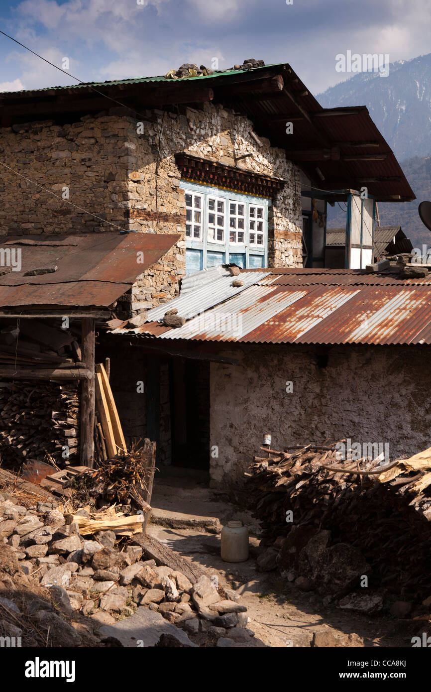 India, Arunachal Pradesh, Tawang Valley, Lhou village, fuel wood pile of traditional stone built tower house Stock Photo