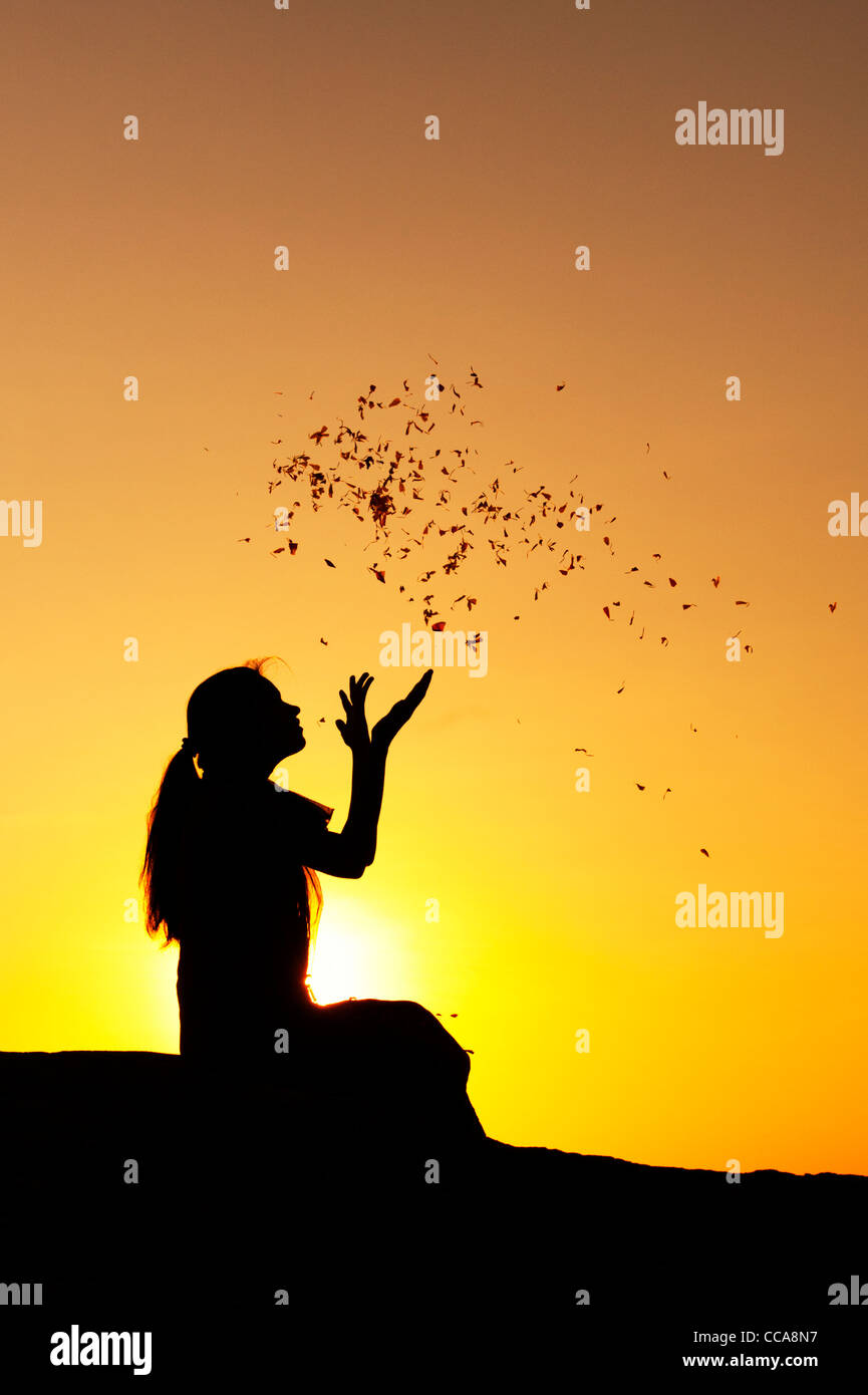 Indian girl throwing flower petals into the air. Silhouette. Andhra Pradesh, India Stock Photo