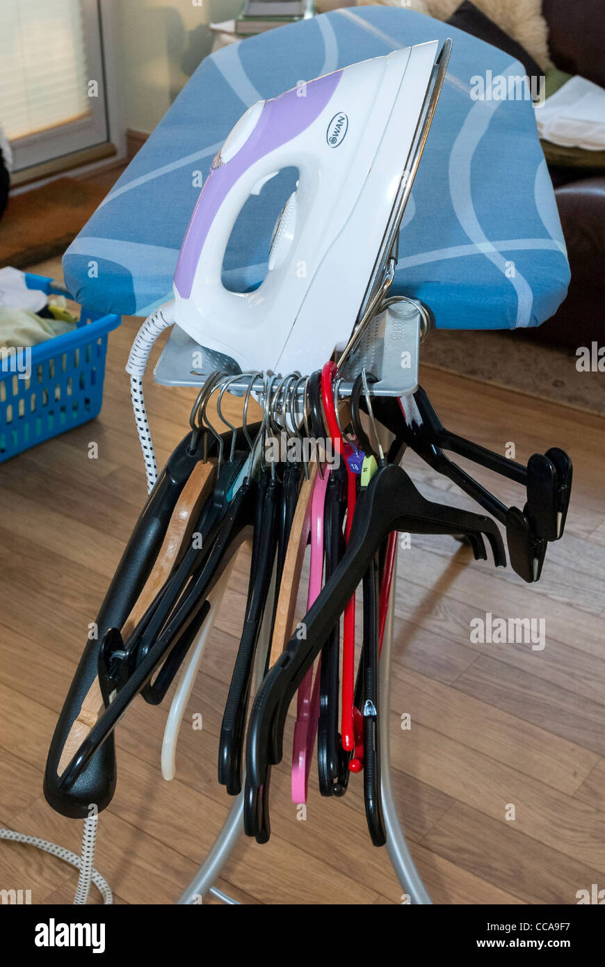 An electric steam iron and coat hangers on an ironing board Stock Photo Alamy
