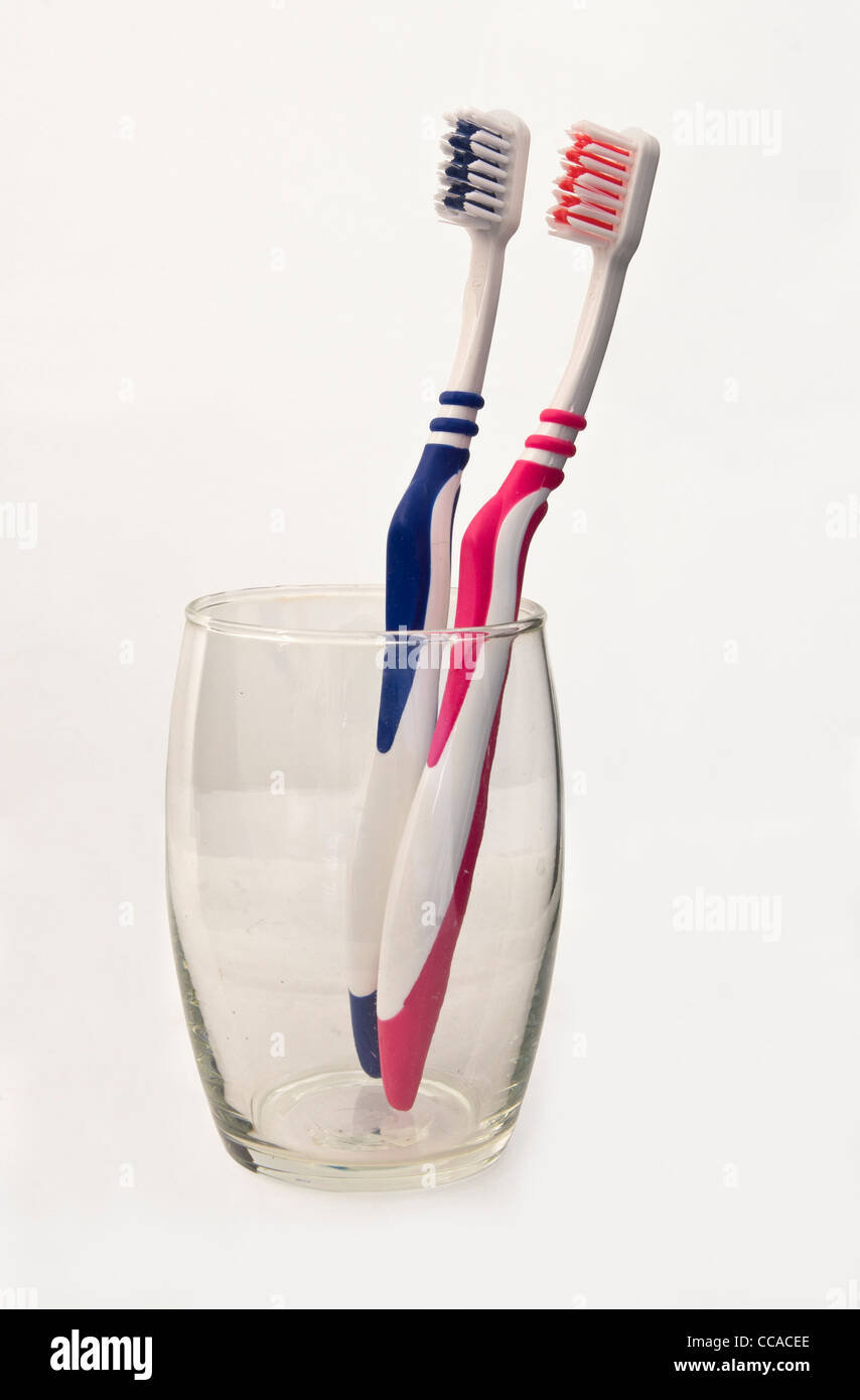 A pink toothbrush and a blue toothbrush side by side in a glass Stock Photo