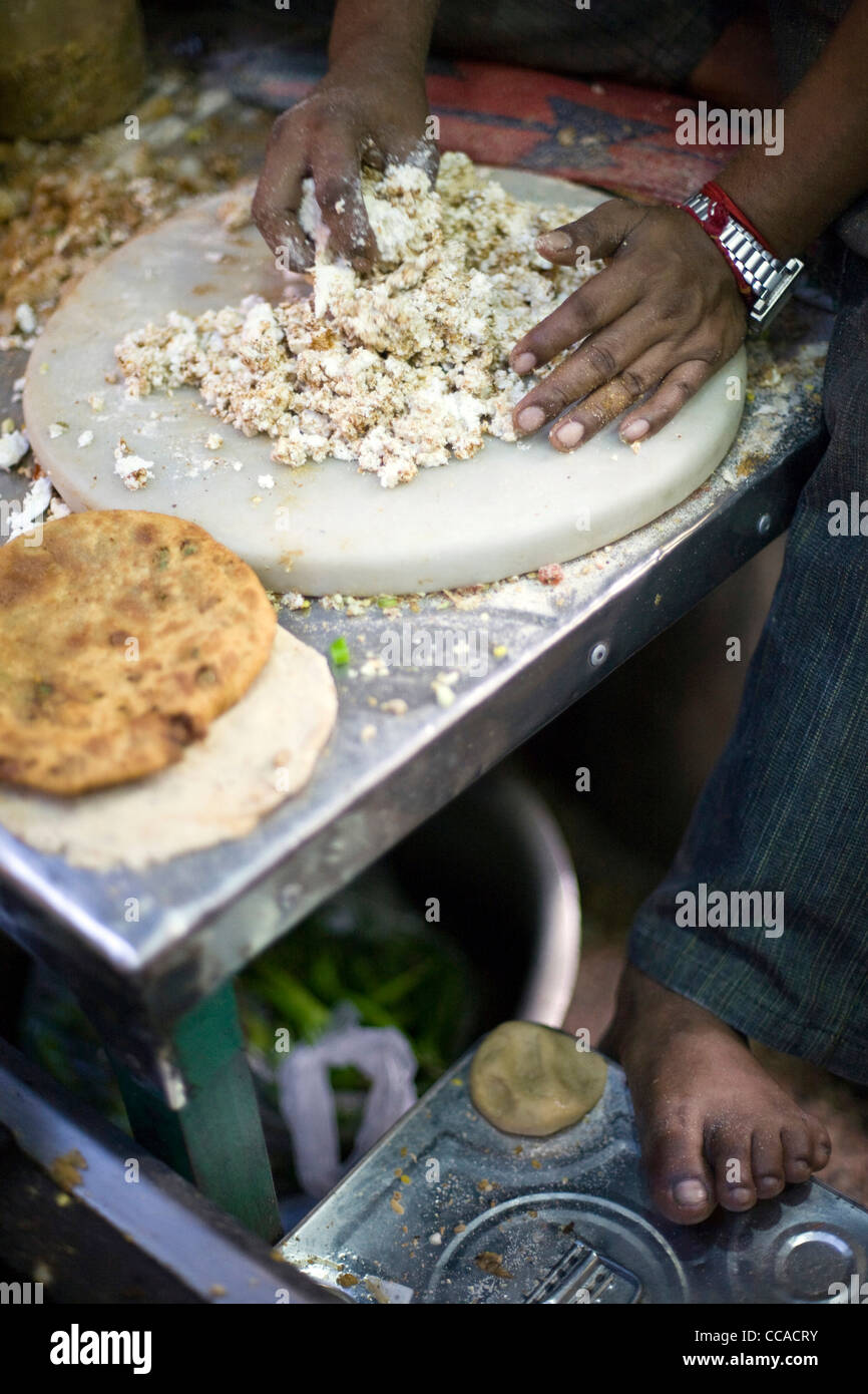 Ram Billas's foot resting on a tin whilst making paratha at Parawthe Wala restaurant in Old Delhi, India Stock Photo