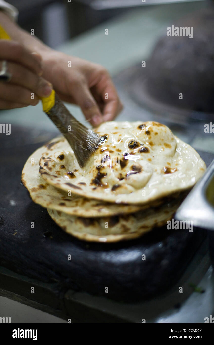 A chef brushes chapati bread with ghee (clarified butter) at the Village Restaurant in Siri Fort, New Delhi Stock Photo