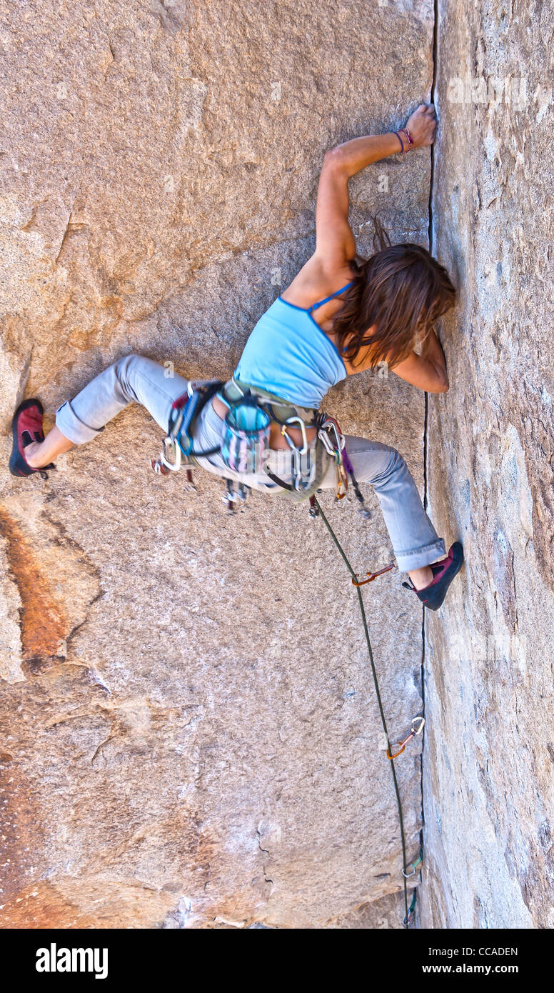Female rock climber struggles to grip the edge of a challenging crack. Stock Photo
