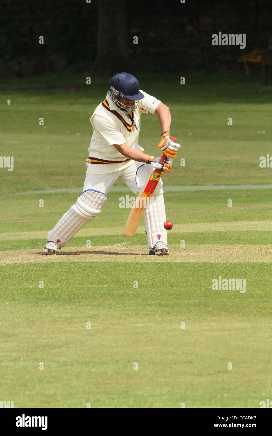 A cricketer in full protective clothing playing a defensive shot Stock Photo