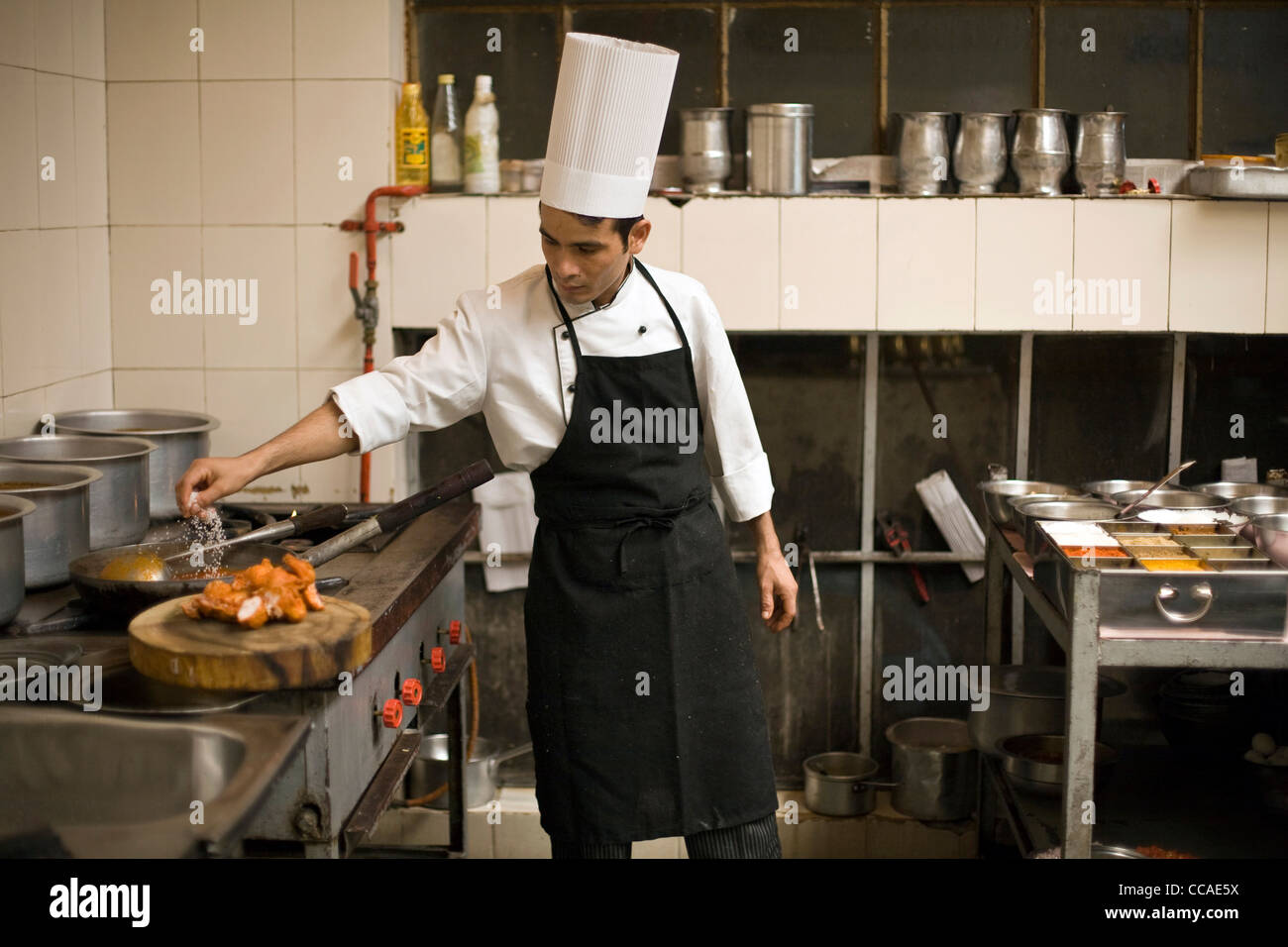 A chef seasons a chicken in preparation for cooking a dish of butter chicken at Moti Mahal Restaurant in Old Delhi, India Stock Photo
