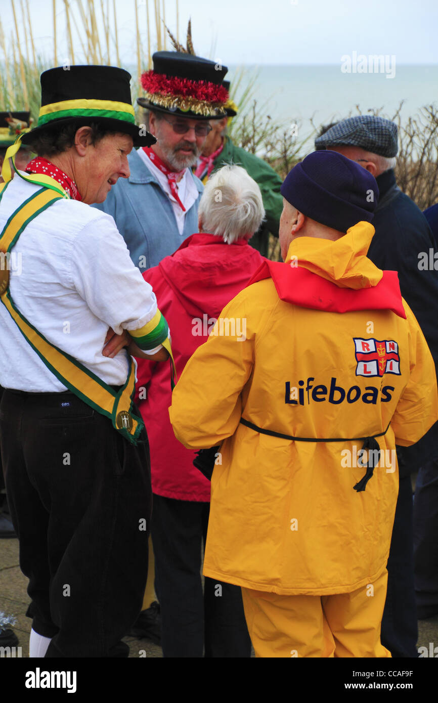 An RNLI Lifeboats volunteer in bright yellow sou'wester uniform wet weather gear on Eastbourne Seafront. Stock Photo