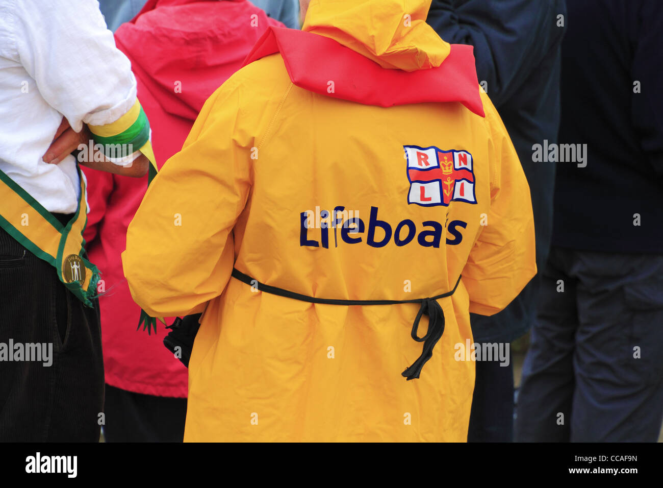 An RNLI Lifeboats volunteer in bright yellow sou'wester uniform wet weather gear on Eastbourne Seafront. Stock Photo