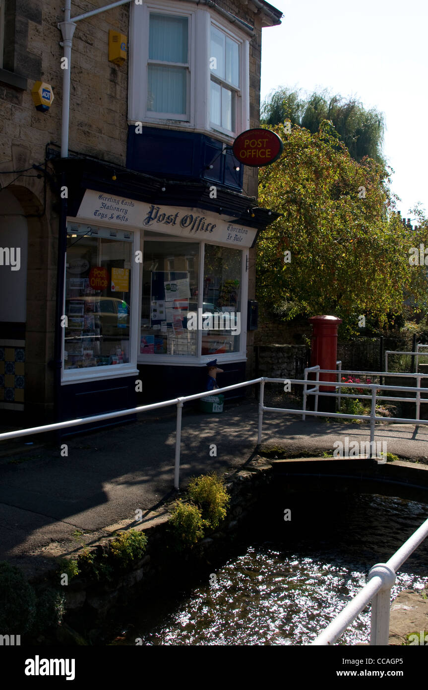 A post office and post box beside a stream that runs through the