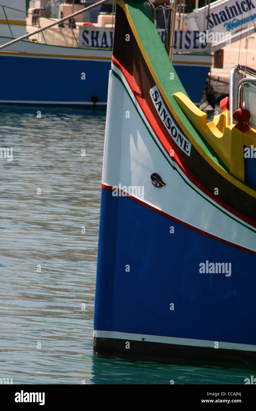 Luzzu boat in Sliemma Harbour in Malta showing colourful markings and eye of Isis and clear water. Stock Photo