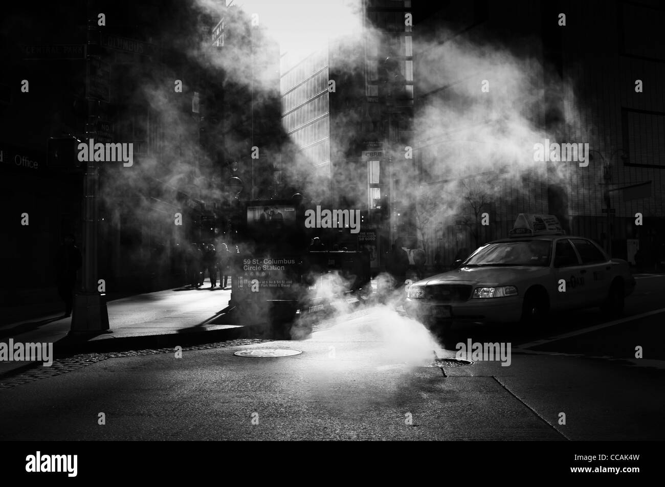 A taxi cab seen driving through a steam cloud by Columbus Circle subway stop on 59th Street in Manhattan, New York City, USA. Stock Photo