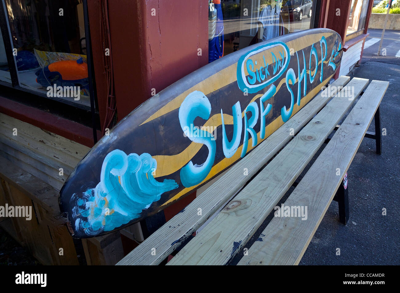 A sign on a surfboard outside a surf shop Stock Photo