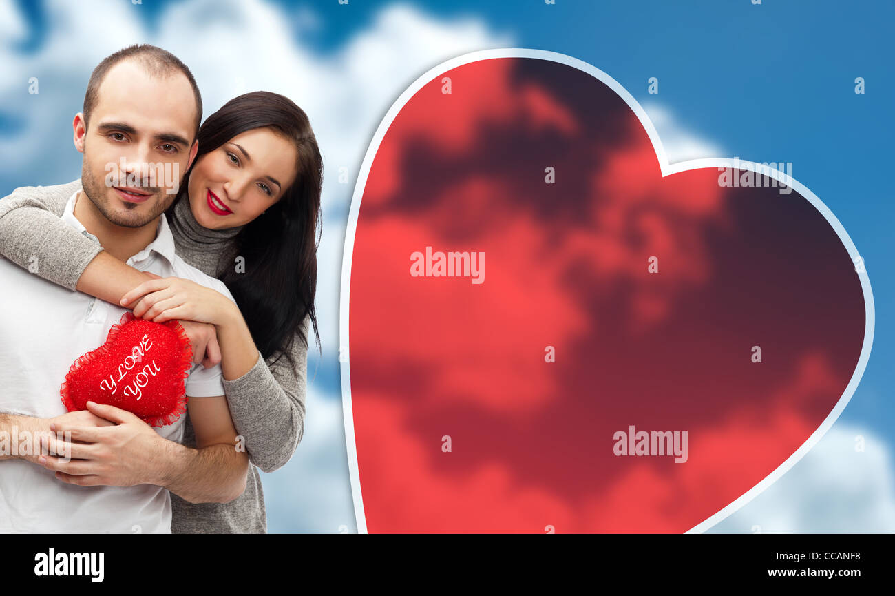 Happy young adult couple with red heart on romantic background with sky ...