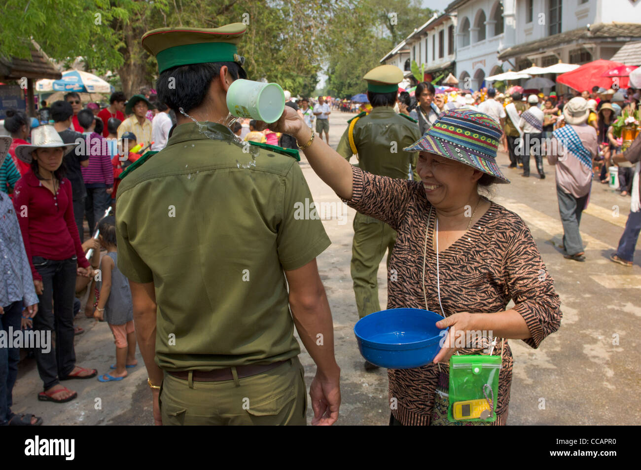 Gleeful Lao woman pouring water onto a policeman as a blessing, Lao New Year (Pi Mai Lao), Luang Prabang, Laos Stock Photo