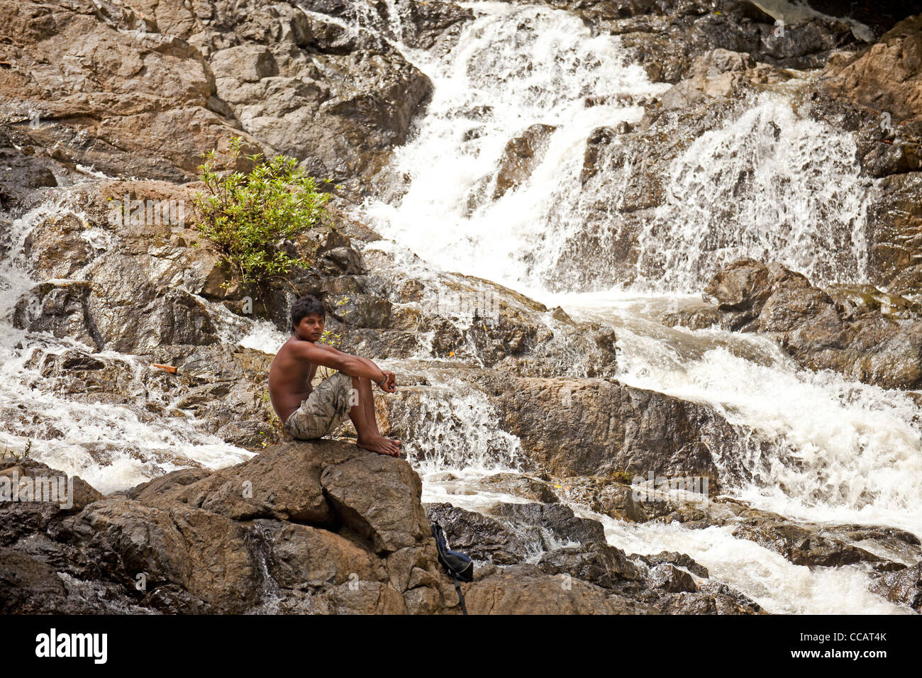 local man sitting at the cascades of Montezuma Waterfall, Montezuma, Nicoya Peninsula, Costa Rica, Central America Stock Photo