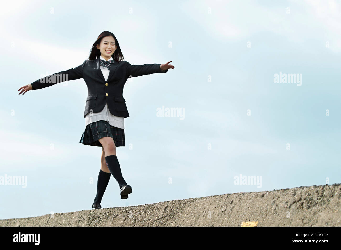 High school girl walking on top of a breakwater Stock Photo