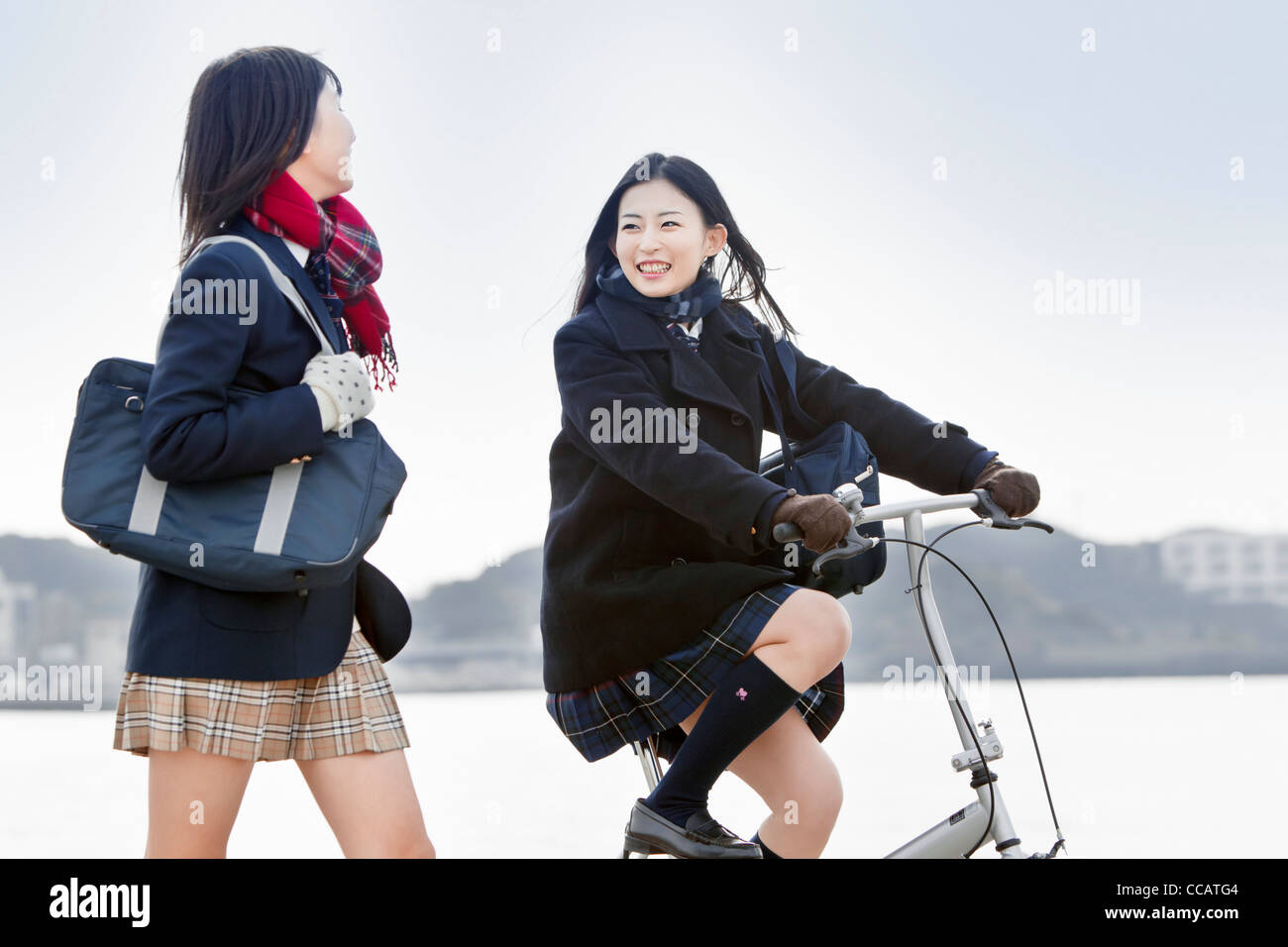 Two high school girls walking and cycling Stock Photo
