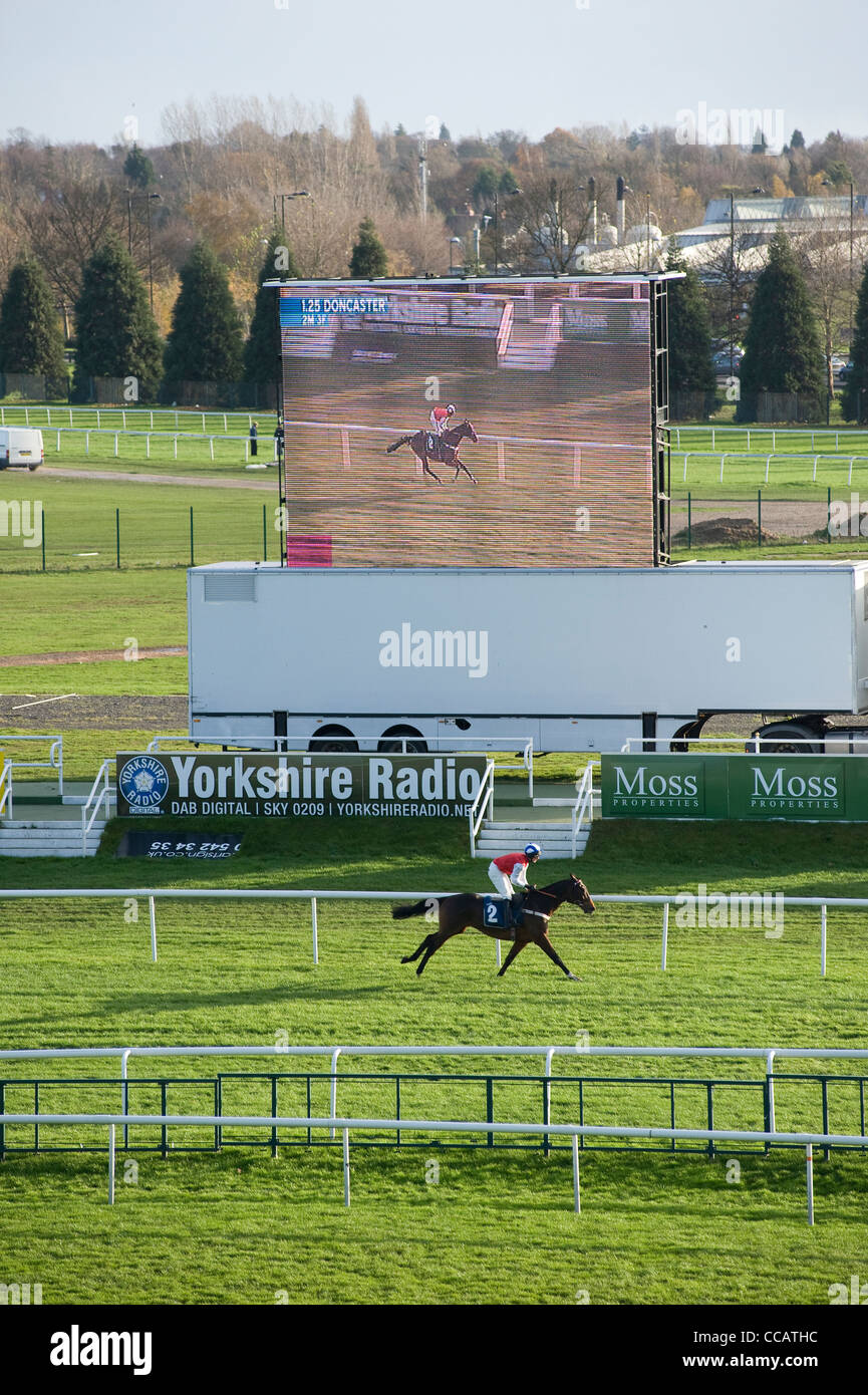 Race horse running to winning post, with big screen behind. Doncaster ...