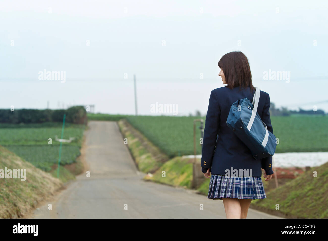 High school girl walking on rural road Stock Photo