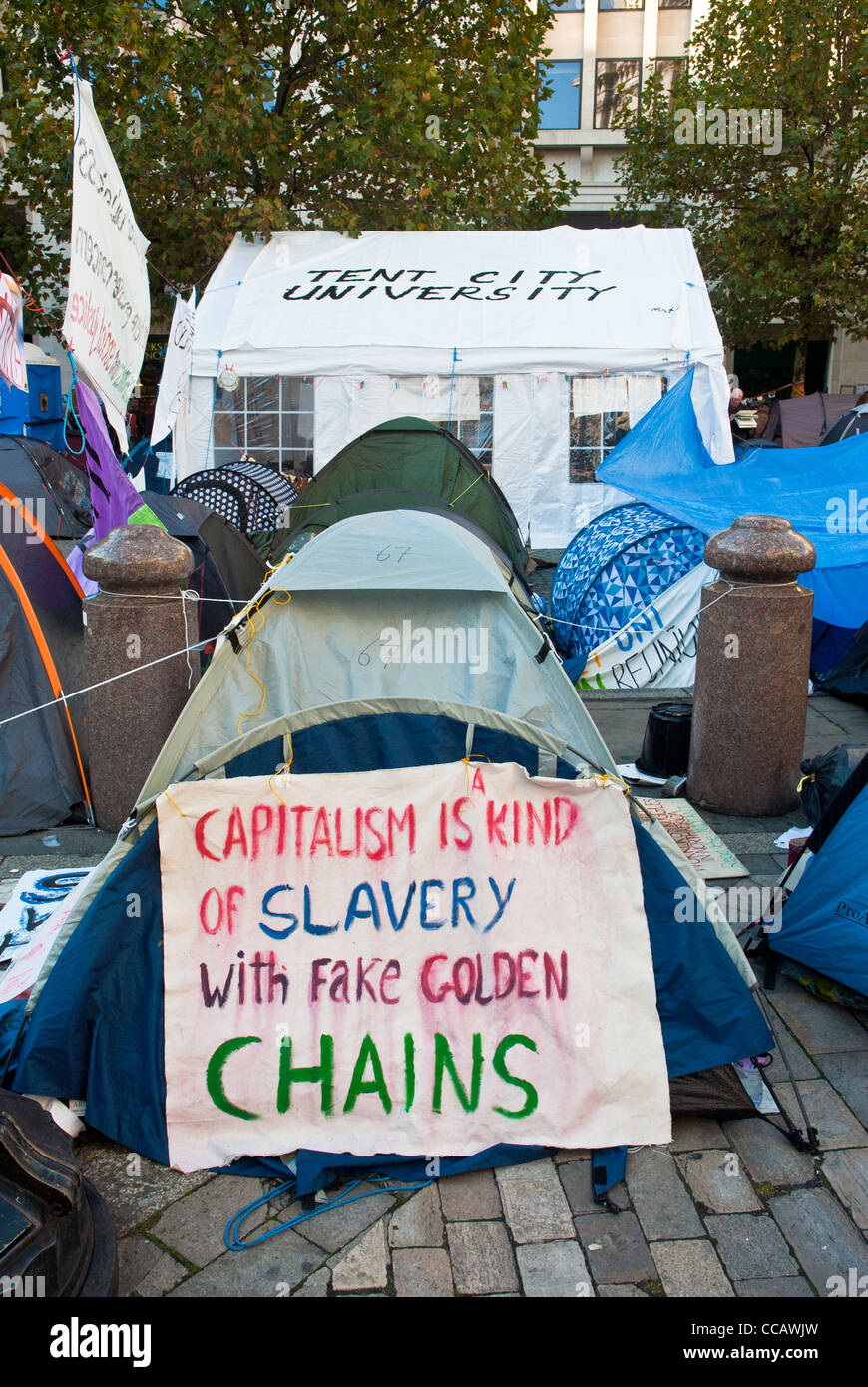 Occupy London St Pauls, banner 'Capitalism is a kind of slavery with fake golden chains' and behind 'Tent City University'. Stock Photo