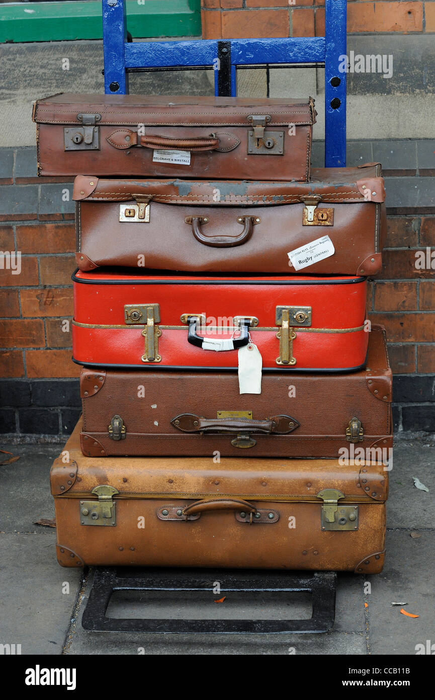 old luggage suitcases stacked on a wheeled trolley england uk Stock