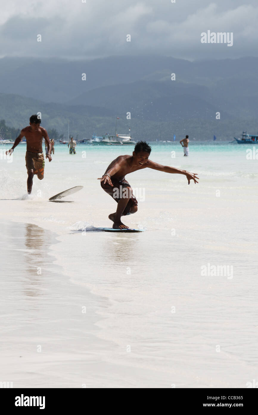 Boracay Island, Philippines – February 21, 2009: Teenagers doing skimboarding at the white sand beach of Boracay. (Editorial) Stock Photo