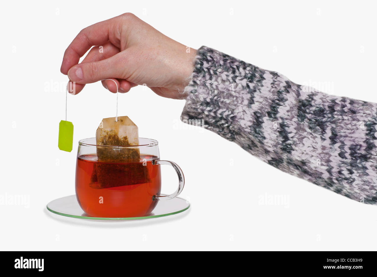 aus einer Tasse mit Tee wird der Teebeutel herausgezogen | the tea bag is pulled out of a cup with tea Stock Photo