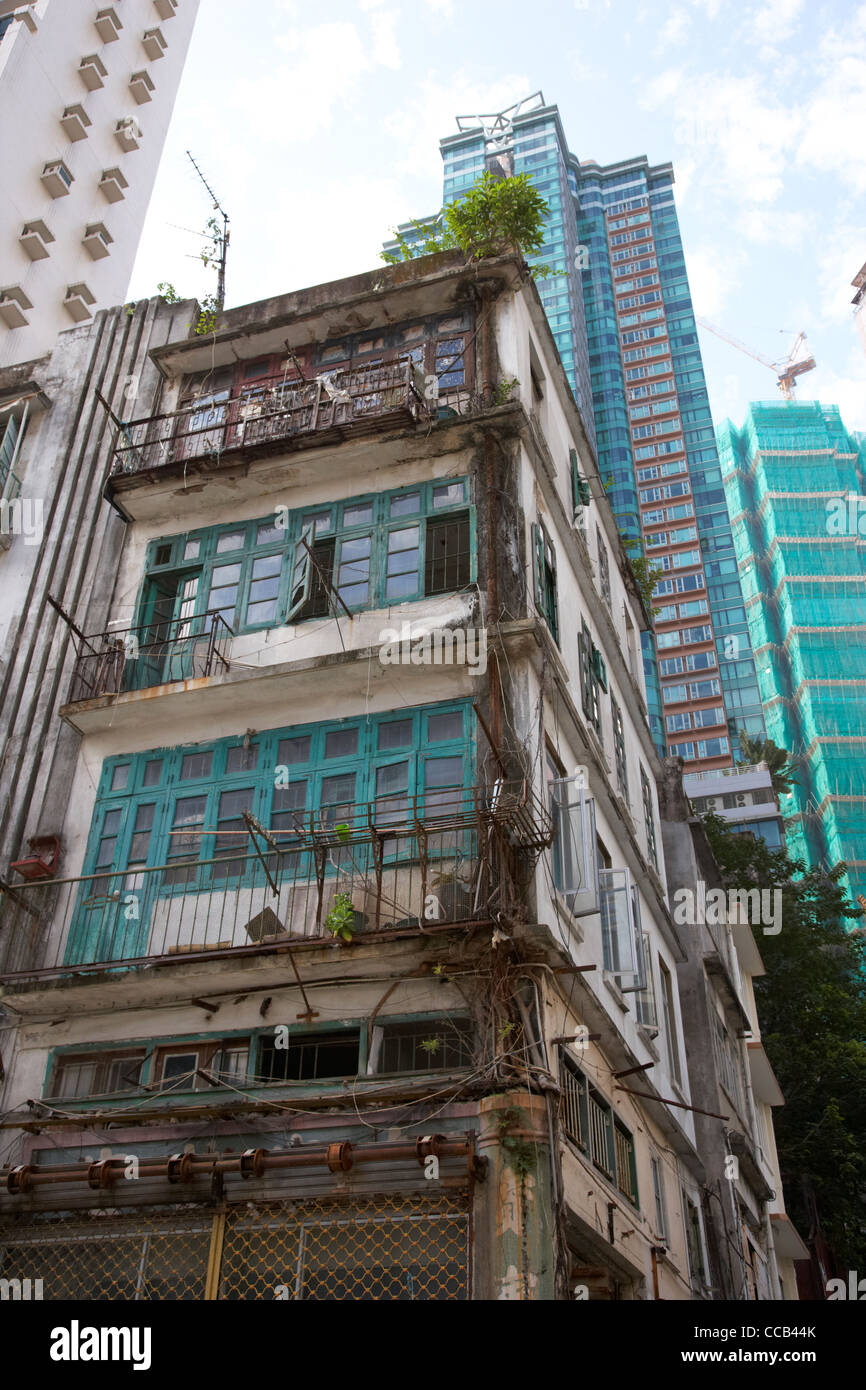 old 4 storey housing building in between apartment skyscrapers hong kong hksar china asia Stock Photo