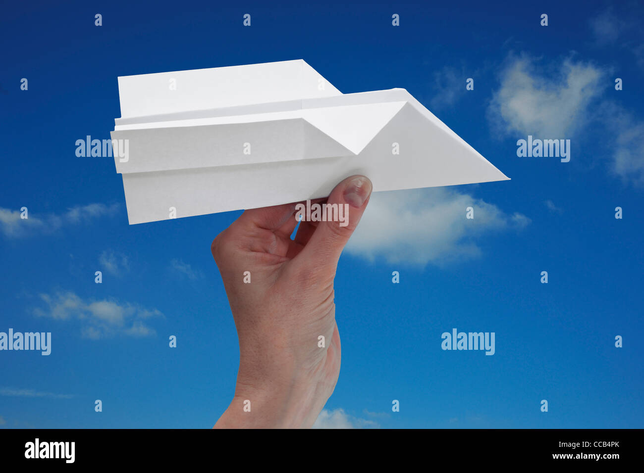 ein Papierflugzeug vor blauem Himmel wird in der Hnad gehalten| a paper plane in front of blue sky is hand-held Stock Photo