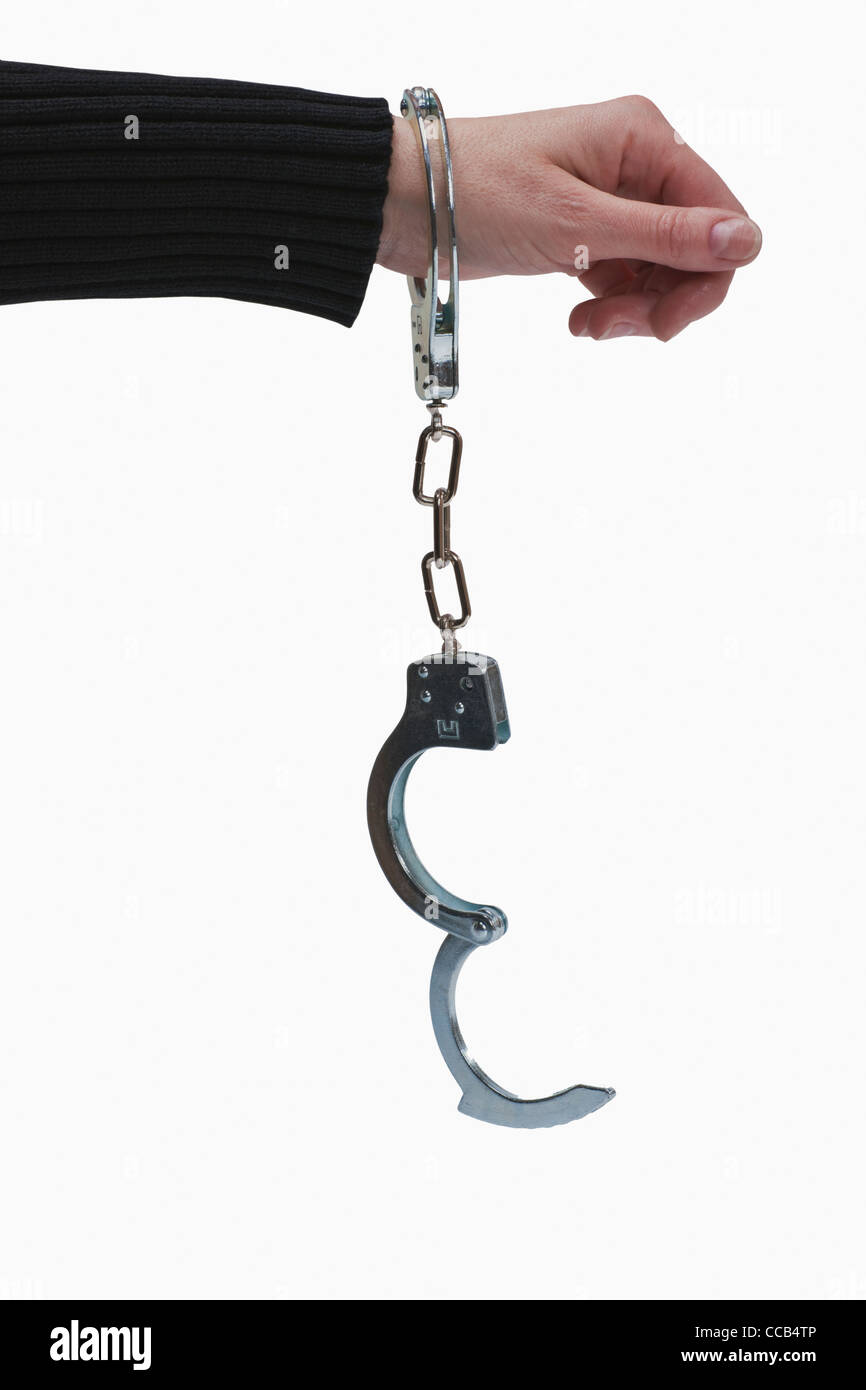 ein Mensch hat eine, durch Handschellen, gefesselte Hand | a man has one hand tied up by handcuffs Stock Photo