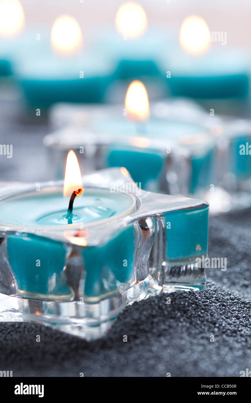 Close-up of blue candles in star shape holders on silver sand Stock Photo