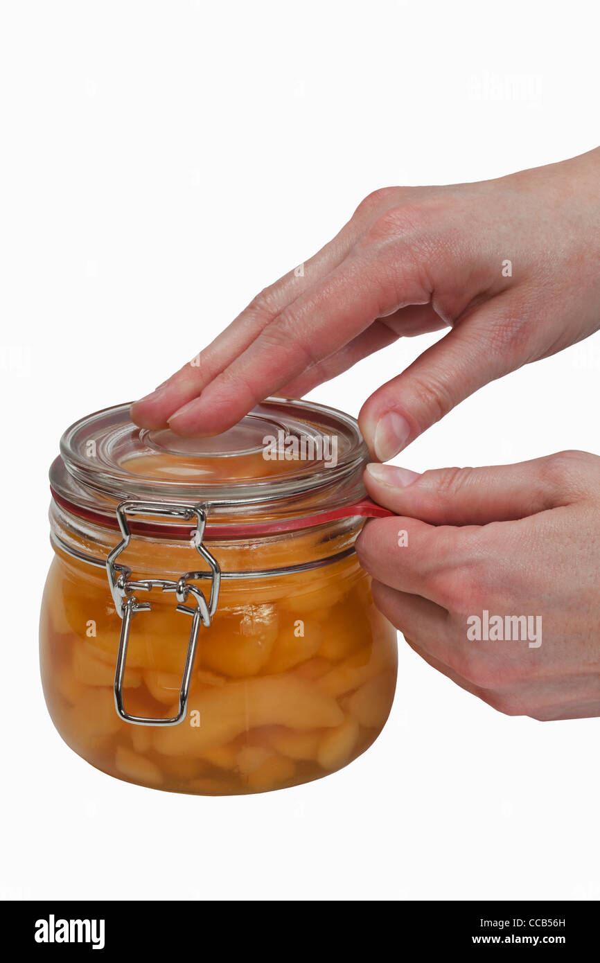 Ein Glas mit eingeweckten Birnenstückchen wird geöffnet | a jar with home canned pieces of pears will be opening Stock Photo