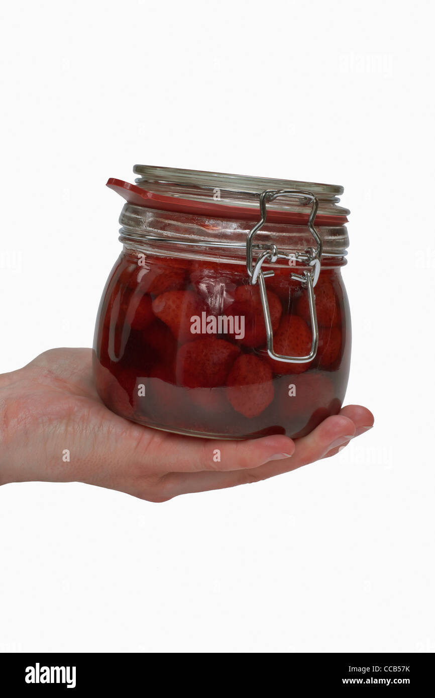 Ein Glas mit eingeweckten Erdbeeren wird in der Hand gehalten | a jar with home canned strawberries is hand-held Stock Photo