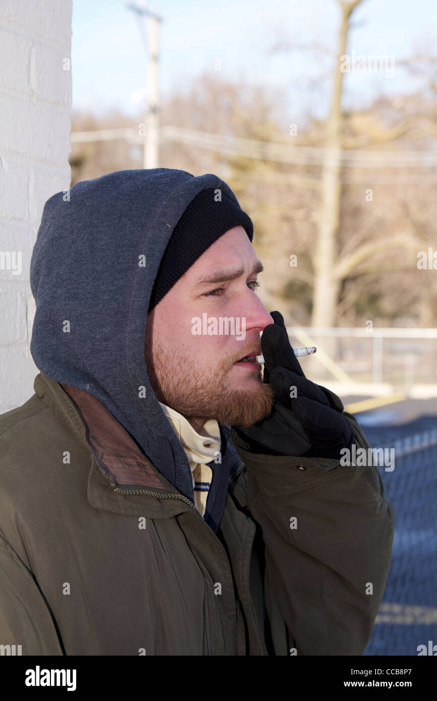 Homeless man smoking cigarette on cold winter day. Stock Photo