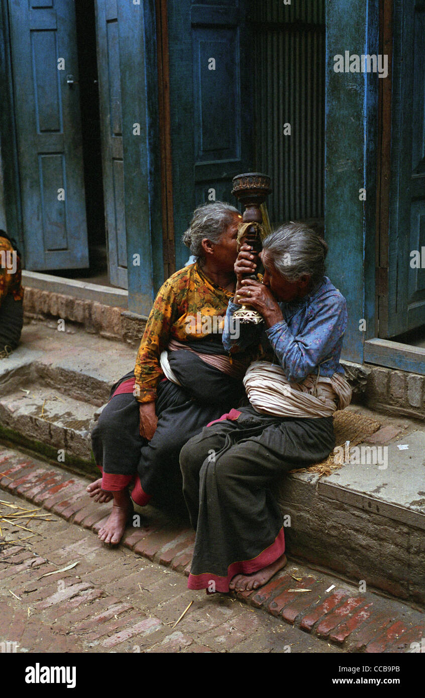 Old women smoke hashish from a traditional pipe. Bhaktapur, Nepal. Stock Photo