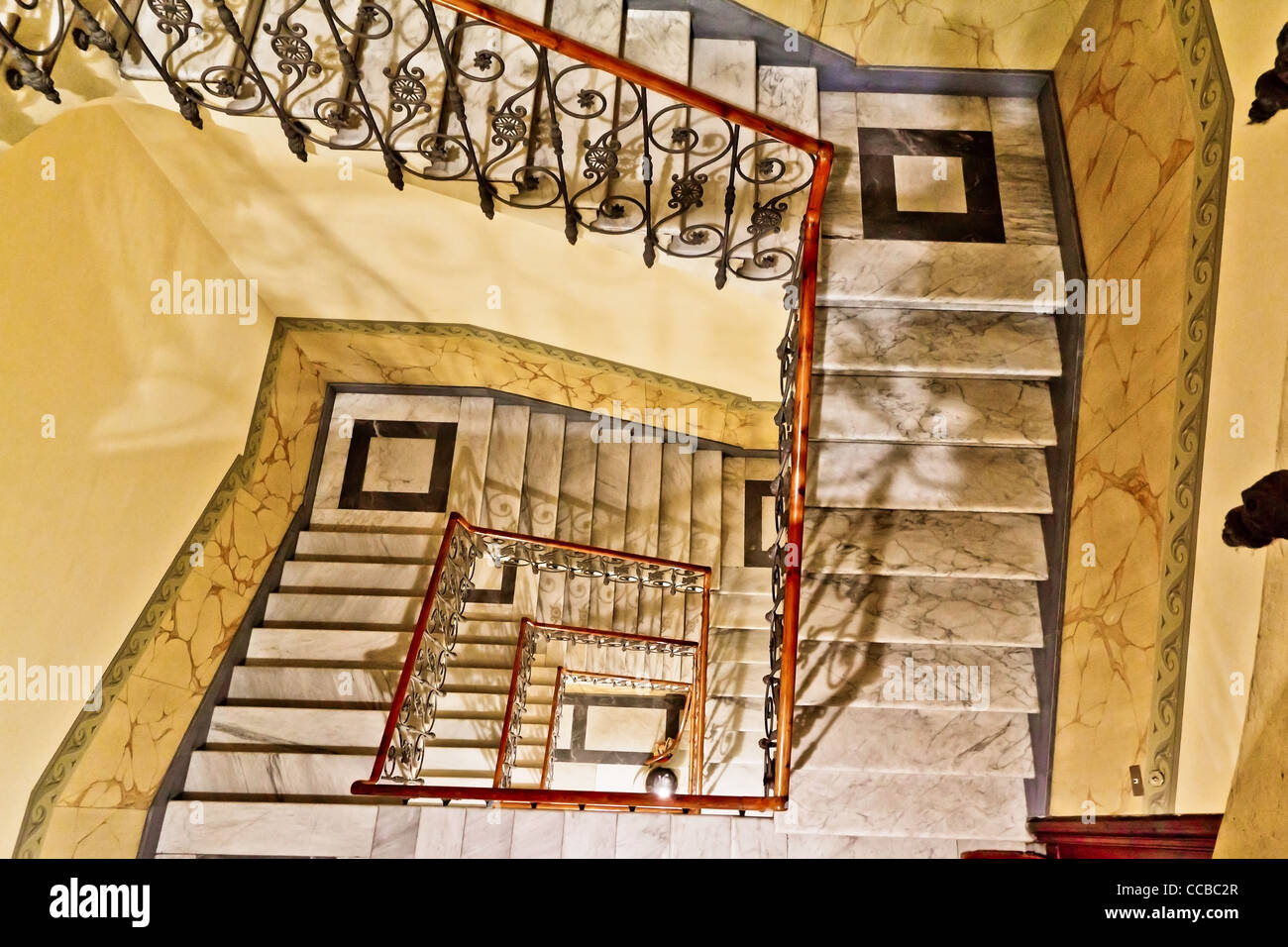 Looking down a winding marble staircase with a metal rail Stock Photo