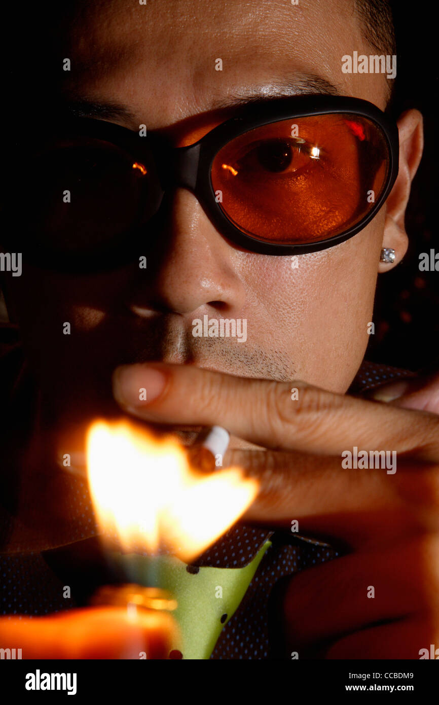 close up of man lighting cigarette while wearing sunglasses Stock Photo