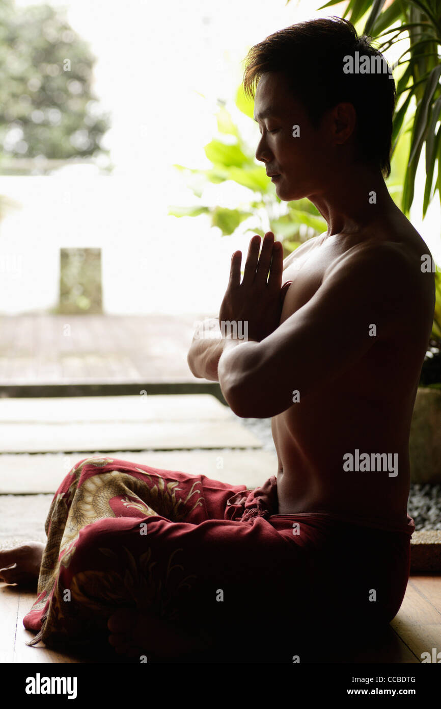 Profile of man sitting crossed legged and meditating Stock Photo - Alamy