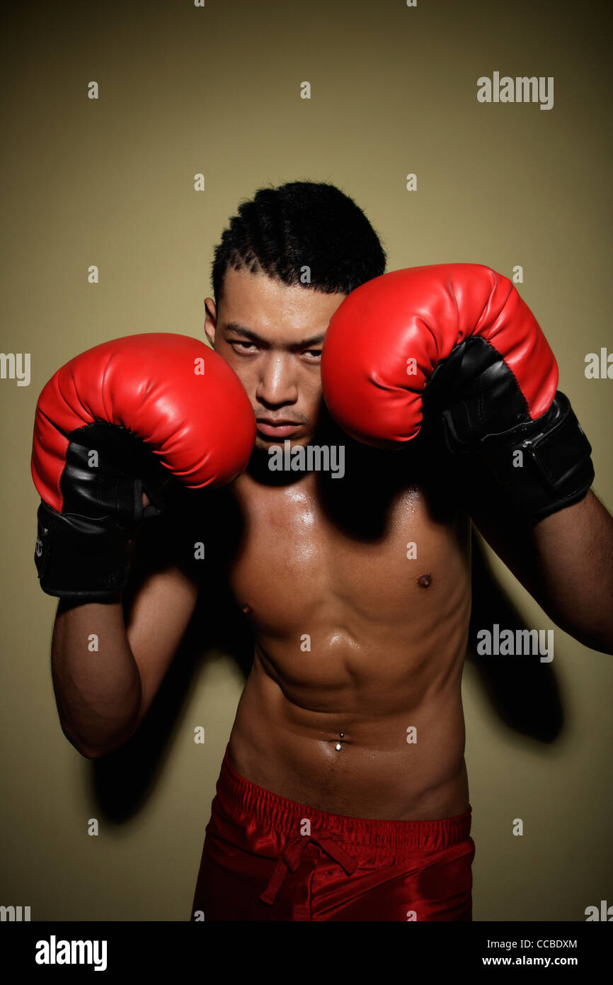 young man guarding his face with red boxing gloves Stock Photo Alamy