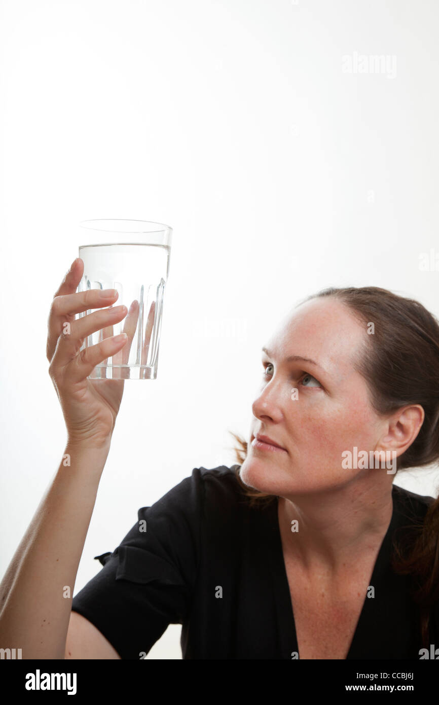 Woman holding and looking at glass of water Stock Photo - Alamy