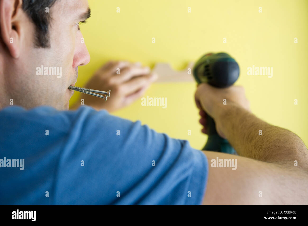 Man using power drill, biting screws in mouth Stock Photo Alamy