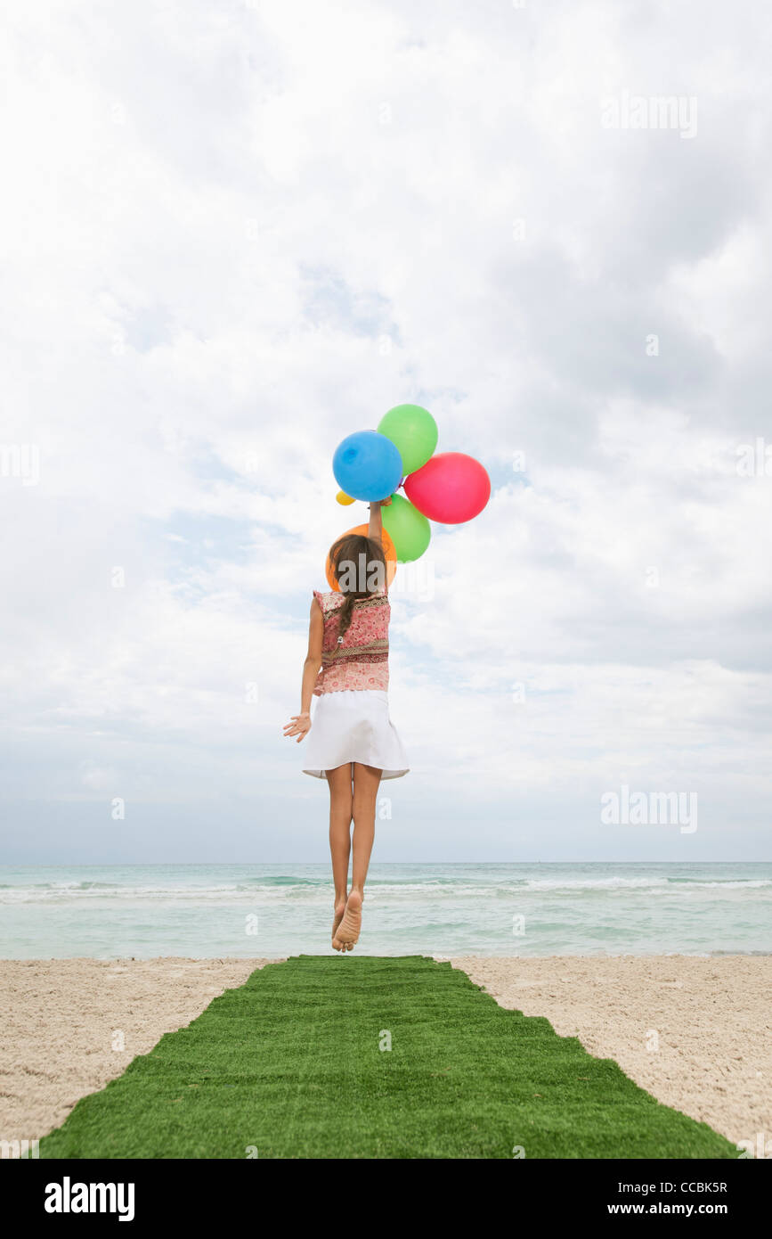 Girl Jumping With Bunch Of Balloons Reaching For Sky Rear View Stock Photo Alamy