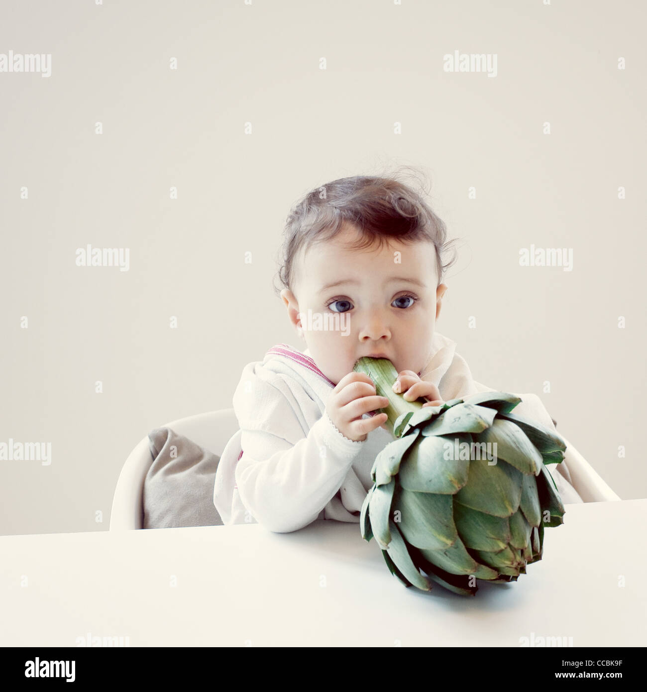 Infant biting fresh artichoke Stock Photo Alamy