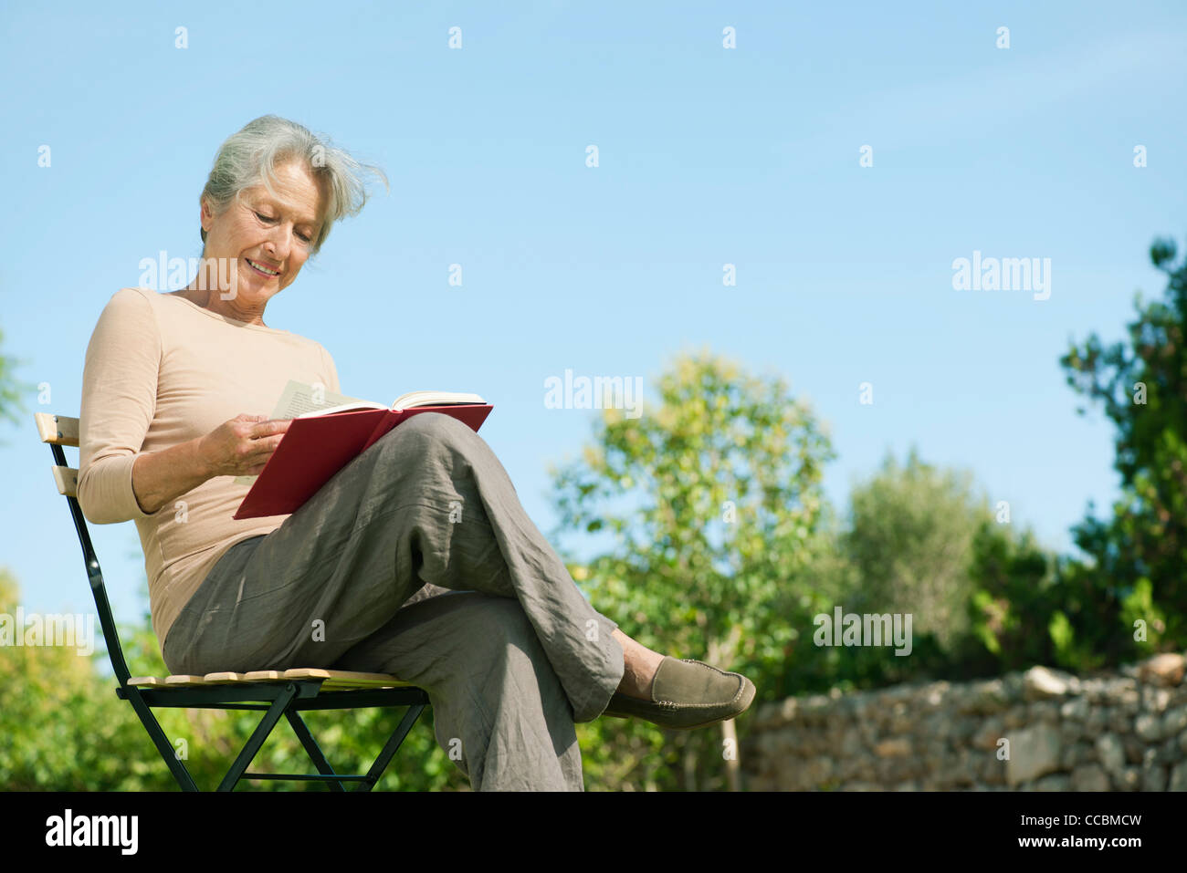 Senior woman reading book outdoors Stock Photo - Alamy