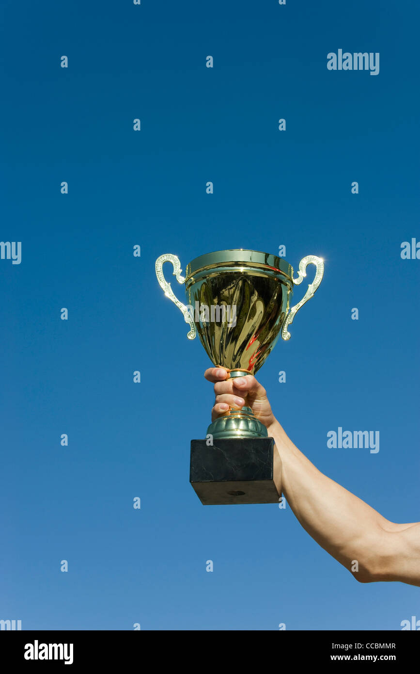Man's arm holding up trophy Stock Photo