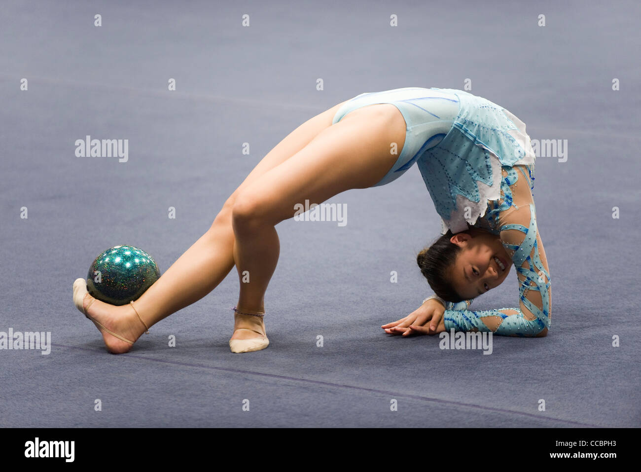 Female gymnast performing floor routine with ball Stock Photo