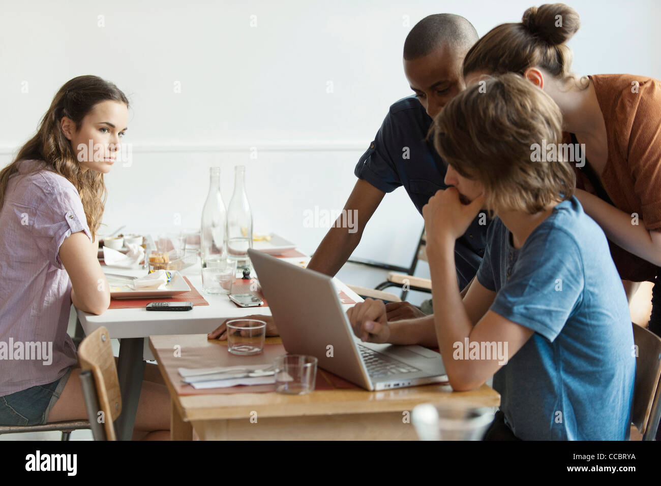 Young woman watching friends using laptop computer Stock Photo