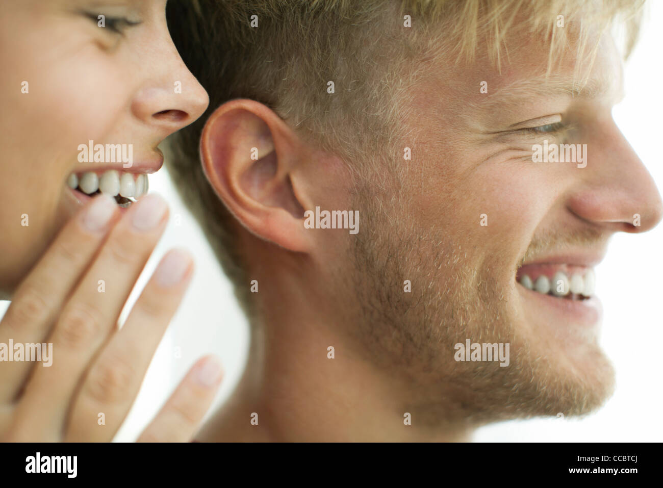 Woman whispering in man's ear, close-up Stock Photo