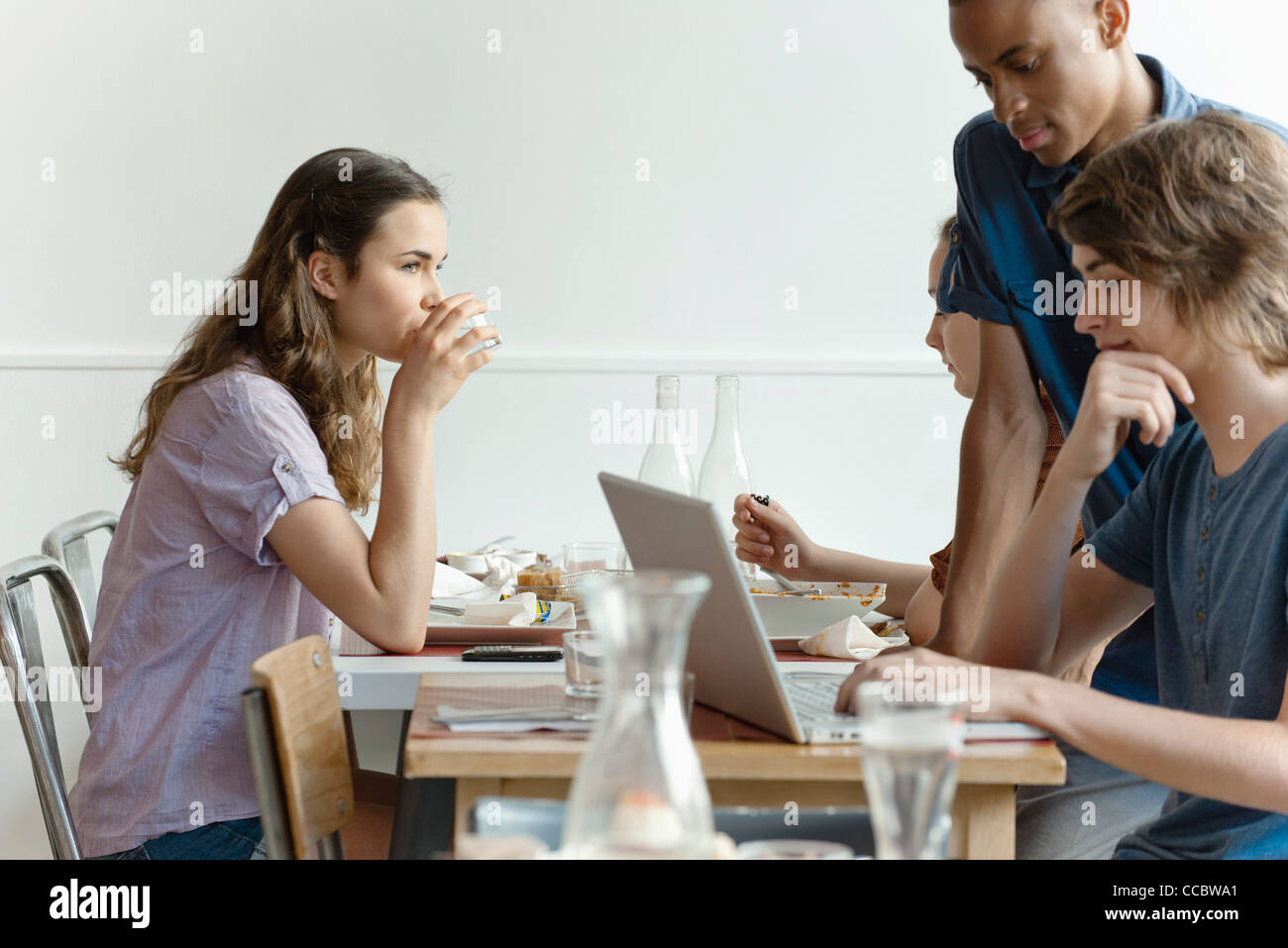 Friends in restaurant, woman dining, man using laptop computer Stock Photo