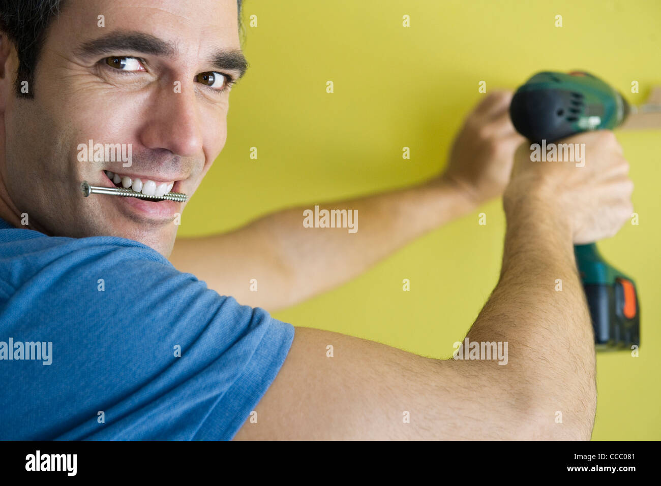 Man using power drill, biting screw in mouth Stock Photo Alamy